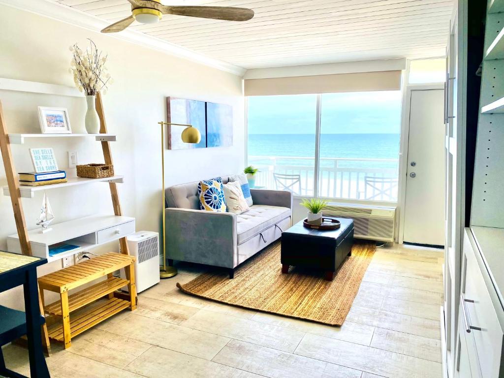 a living room with a couch and a view of the ocean at Sugar Sands - Ocean front at Symphony Beach Club ! in Ormond Beach