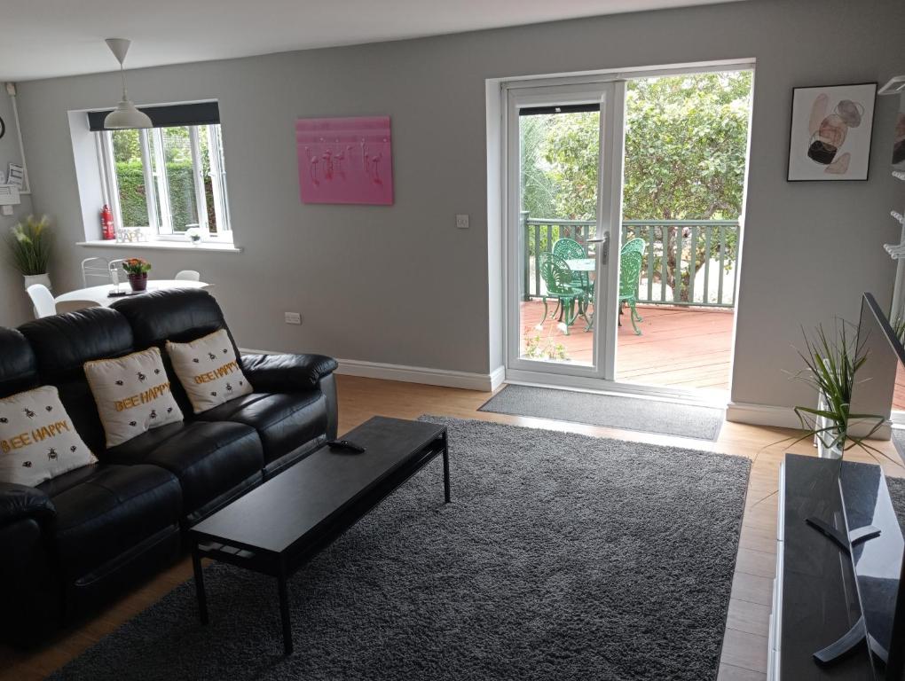 a living room with a black leather couch and a sliding glass door at Green Street Retreat in York