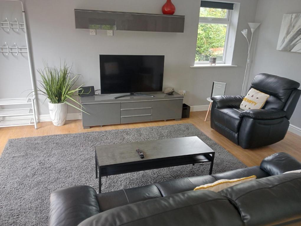 a living room with a black leather couch and a flat screen tv at Green Street Retreat in York