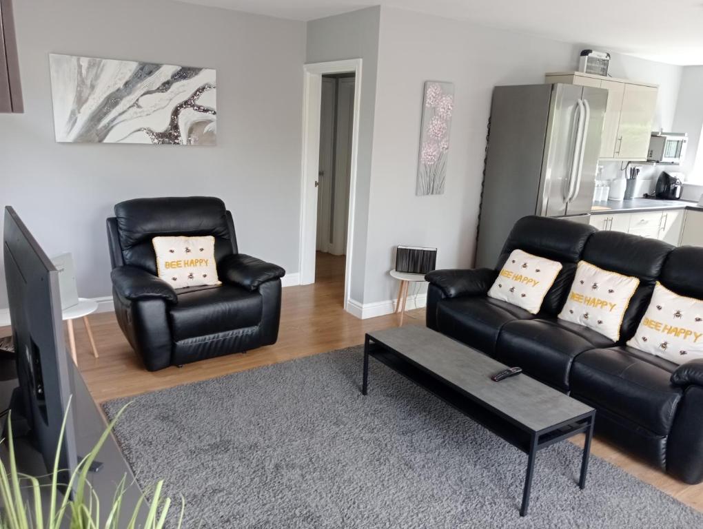 a living room with a black leather couch and two chairs at Green Street Retreat in York