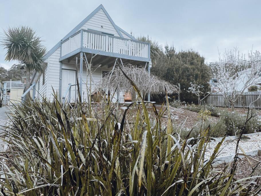 uma casa branca com um alpendre no topo de um quintal em Barefoot Bungalow em Bicheno