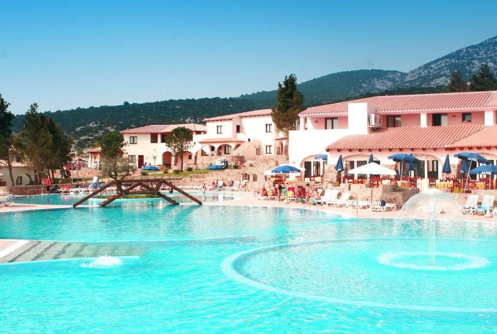 uma grande piscina com água azul num resort em Club Esse Cala Gonone em Cala Gonone