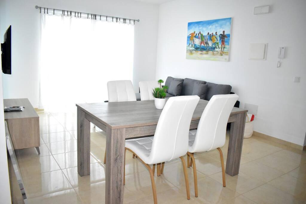 d'une table à manger entourée de chaises blanches. dans l'établissement Lovely - Luxury 3 Bedrooms 500m from the Beach., à Santa Maria