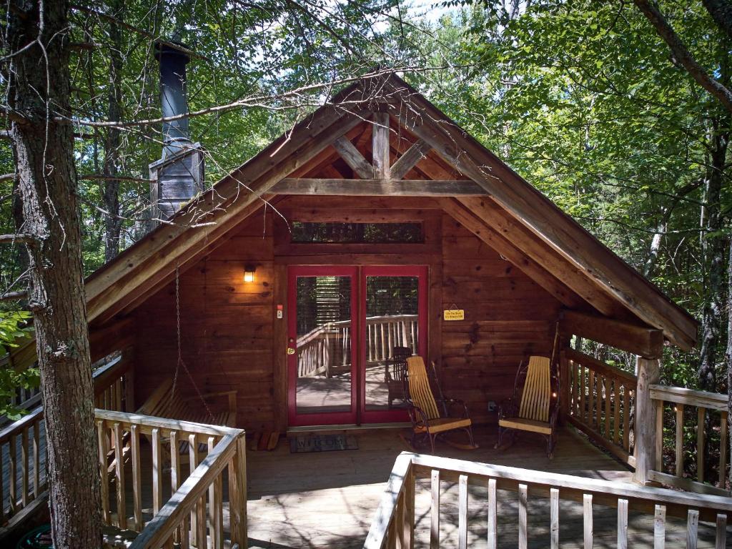 una cabaña con una puerta roja en el bosque en Gatlinburg Area Hottub Cabin - Ladyslipper en Sevierville