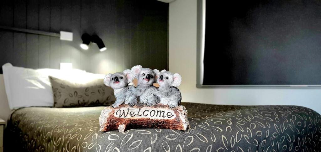 three stuffed animals sitting on top of a bed at Goldrush Motel Young CBD in Young