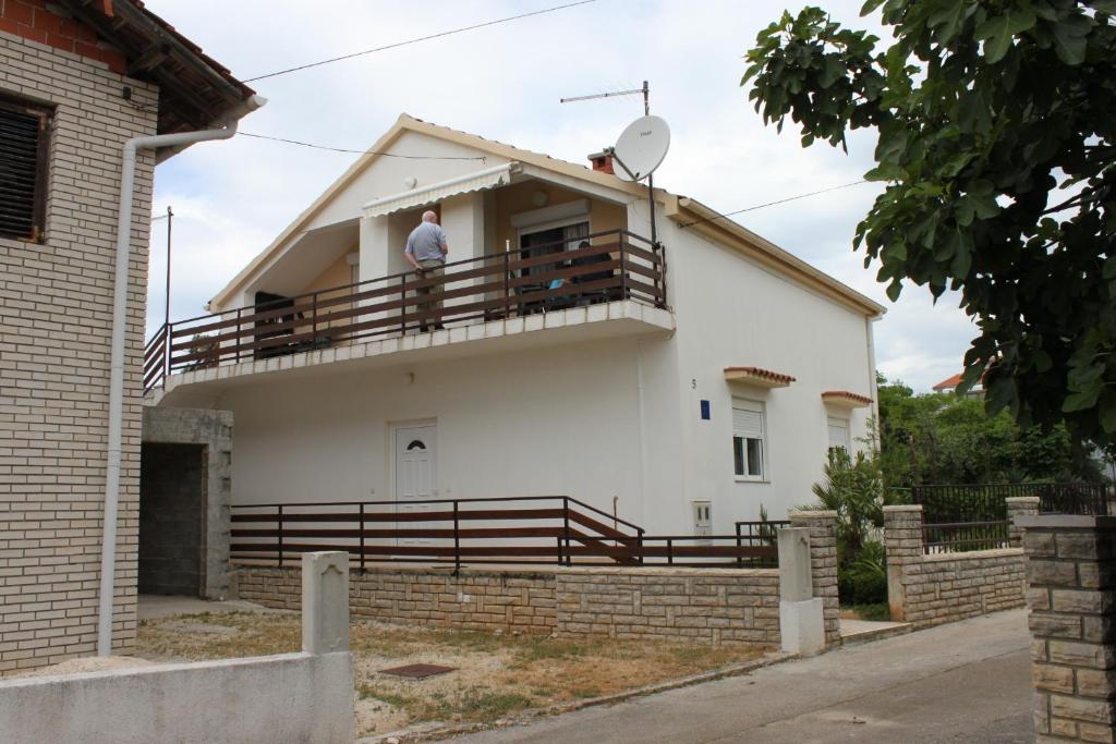 un homme debout sur le balcon d'une maison dans l'établissement Apartments with a parking space Sukosan, Zadar - 6332, à Sukošan