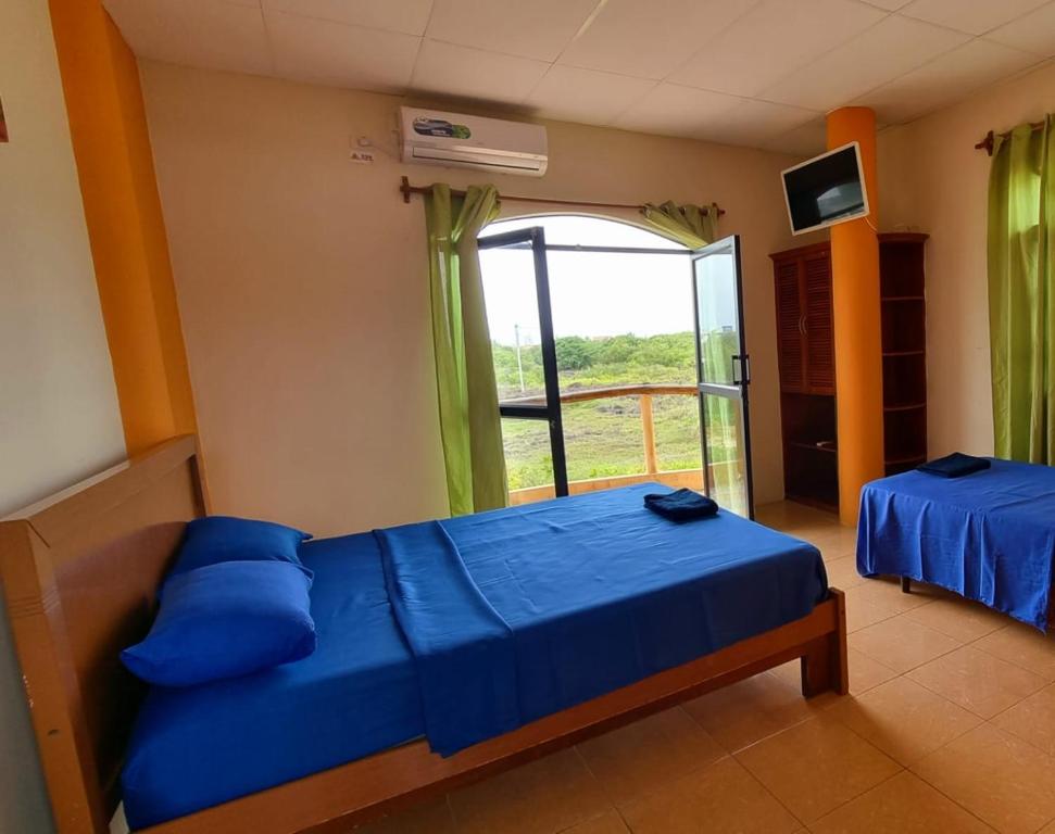 a bedroom with a blue bed and a window at Hostal Poseidon - Neptuno in Puerto Villamil