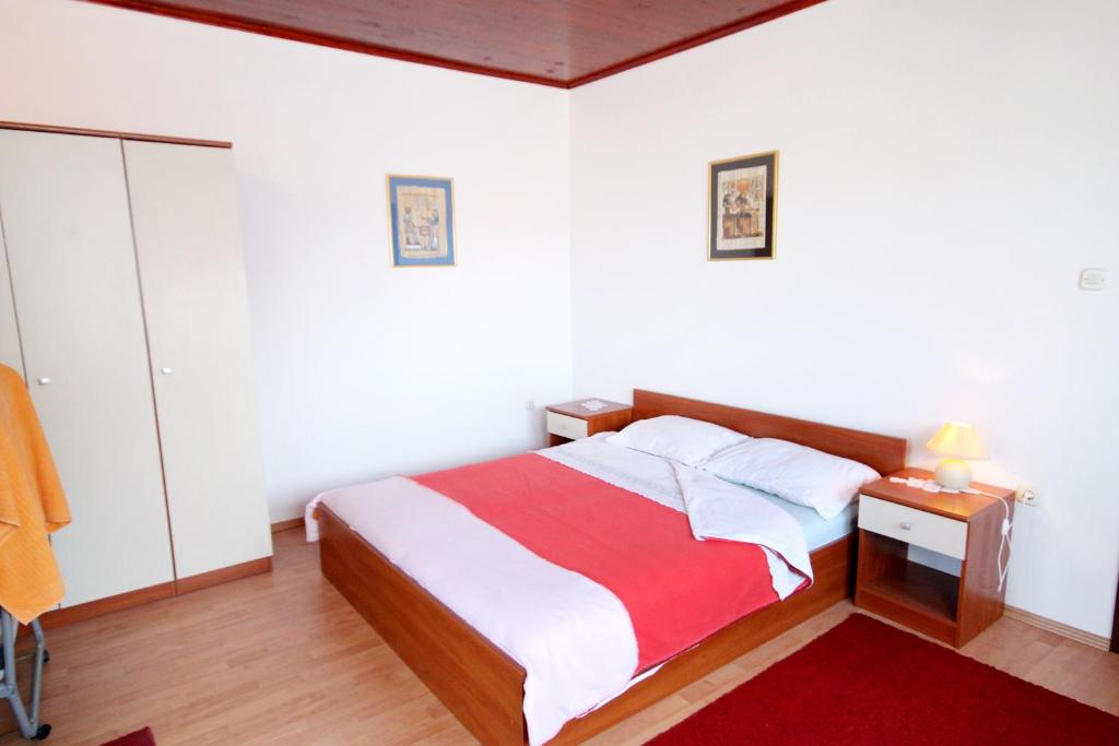 a bedroom with a bed with a red and white blanket at Apartments by the sea Brgulje, Molat - 6250 in Brgulje