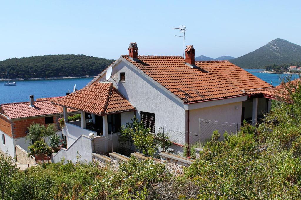 a white house with red roofs on top of a hill at Apartments by the sea Brgulje, Molat - 6243 in Molat