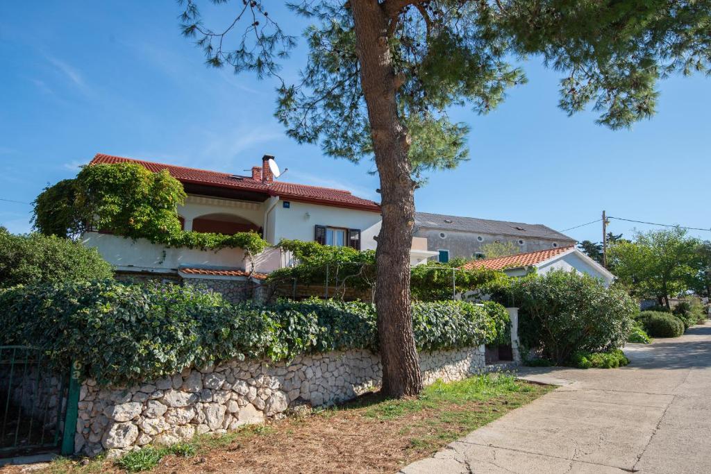 a house with a stone wall and a tree at Apartments with a parking space Molat - 6249 in Molat