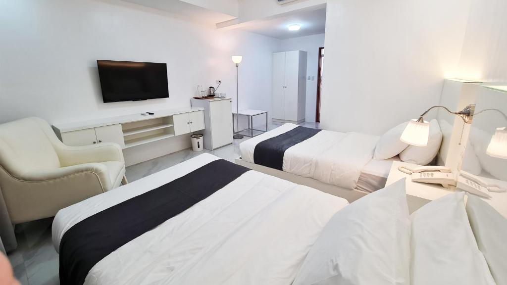 ein Hotelzimmer mit 2 Betten und einem TV in der Unterkunft Staycation Hotel 