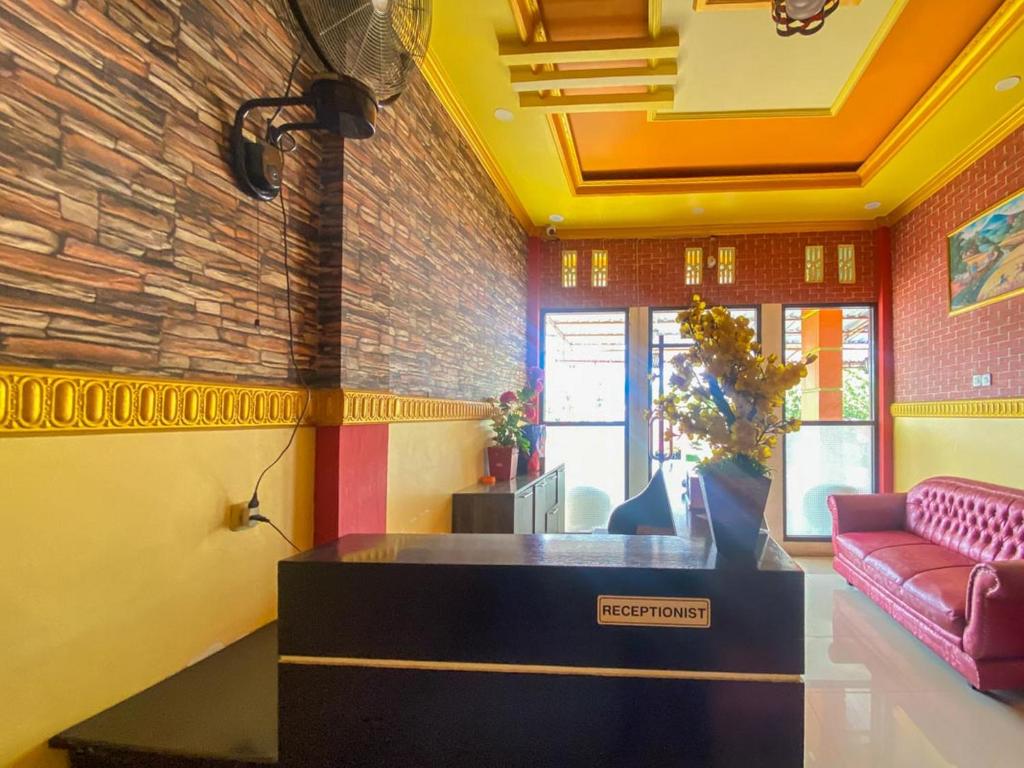 a lobby with a pink couch and a brick wall at Hotel Karunia 2 Jailolo in Porniti