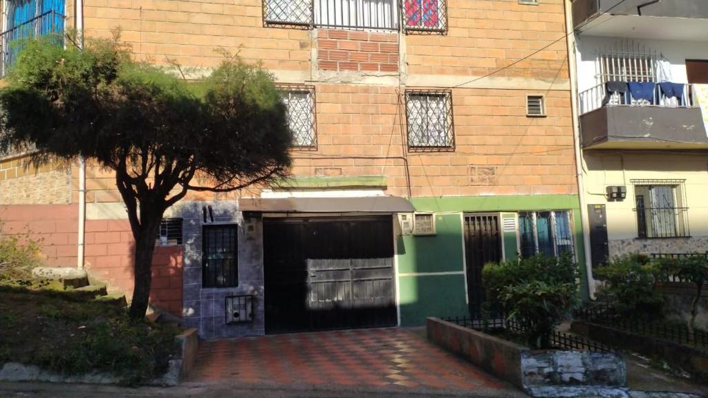 a building with a garage and a tree in front of it at Lugar acogedor y muy central en Medellin in Medellín