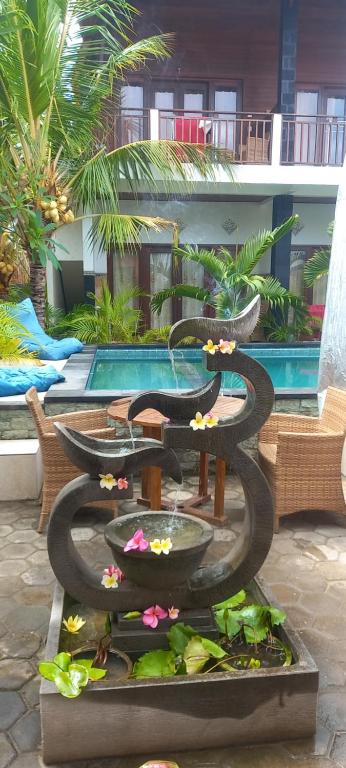 una fuente de agua con flores en un patio en Swara Homestay 2, en Nusa Lembongan