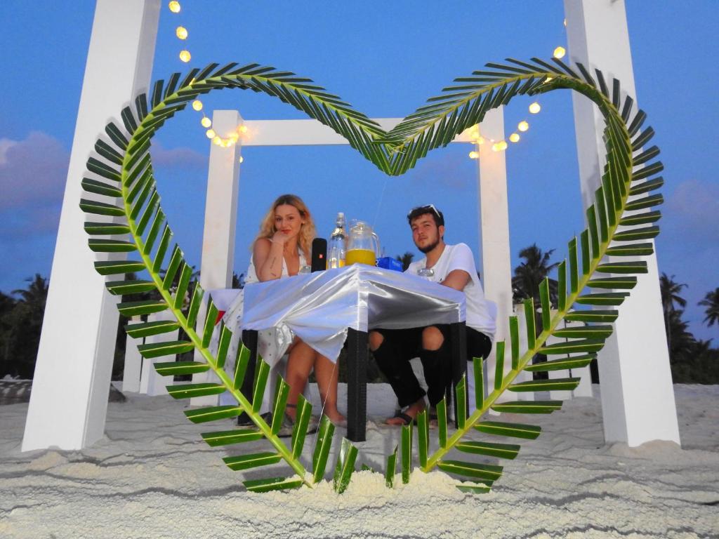 a man and woman sitting at a table in a heart shape at White Sand Himandhoo in Himandhoo 