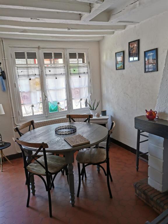 een eetkamer met een tafel, stoelen en ramen bij La Maison d'Yvonne in La Bouille