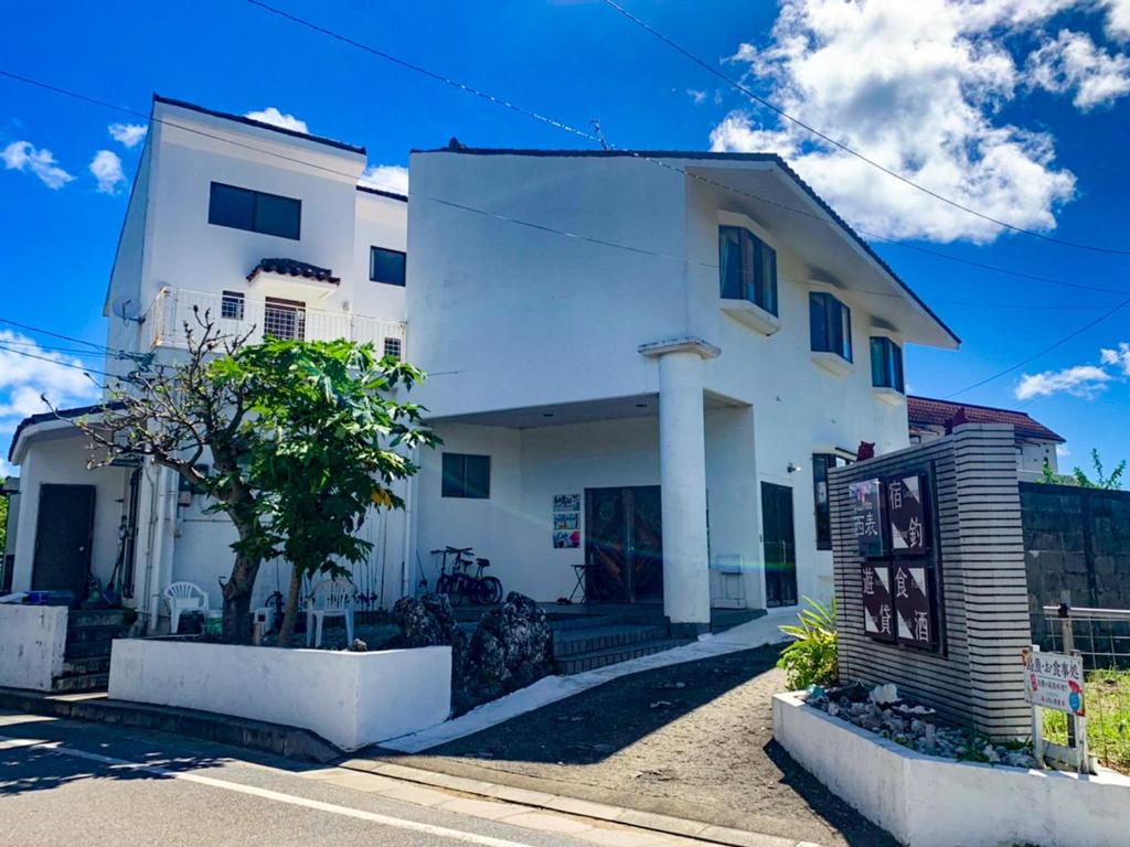 ein weißes Haus mit einem Baum davor in der Unterkunft Sea apple in Iriomote