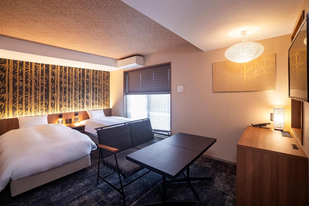 a hotel room with a bed and a desk and a table at Rinn Gion Kenninji in Kyoto