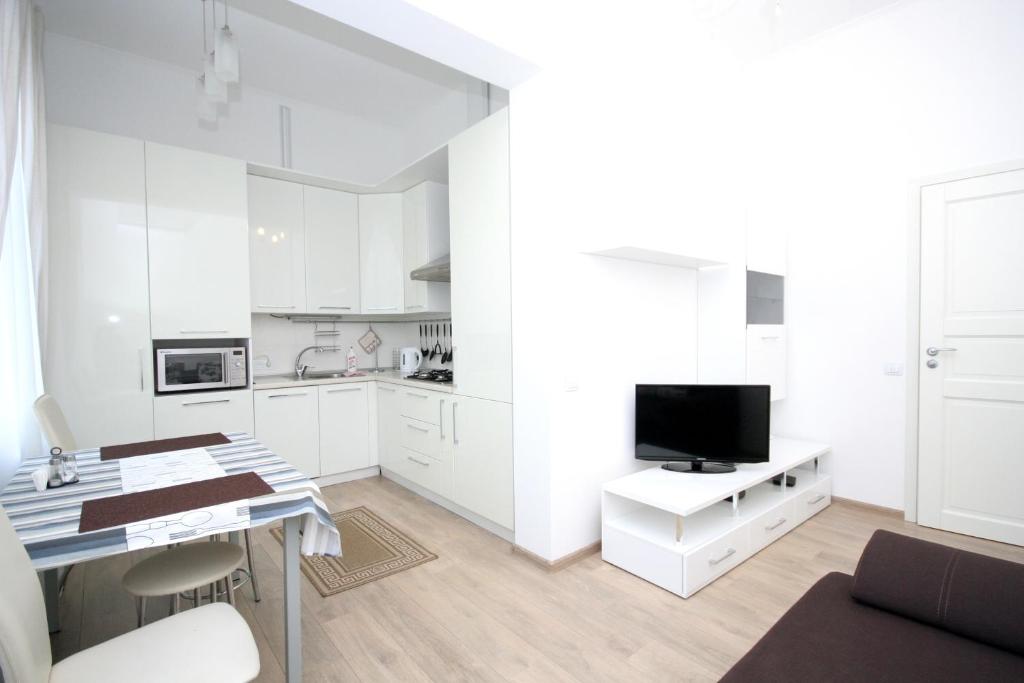eine Küche mit weißen Schränken und einem Schreibtisch mit einem TV in der Unterkunft Real Home Apartments in Kiev Center in Kiew