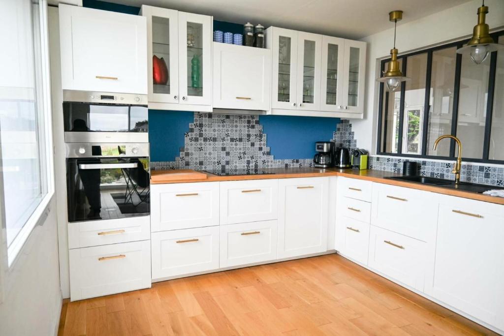 a kitchen with white cabinets and a wooden floor at Résidence Le Lenn-louannec - Maisons &amp; Villas pour 6 Personnes 784 in Lannion