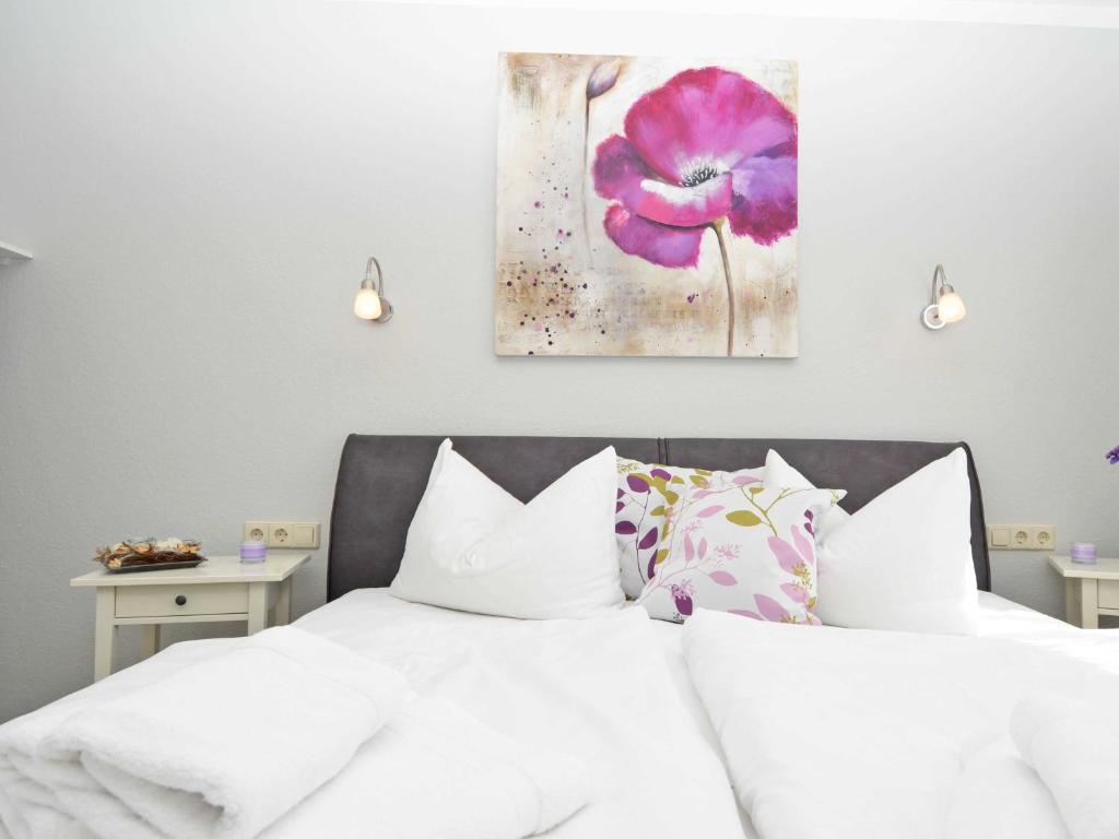 a bedroom with a white bed with a purple flower painting on the wall at Wohnpark Stadt Hamburg - Apt. 22 in Binz