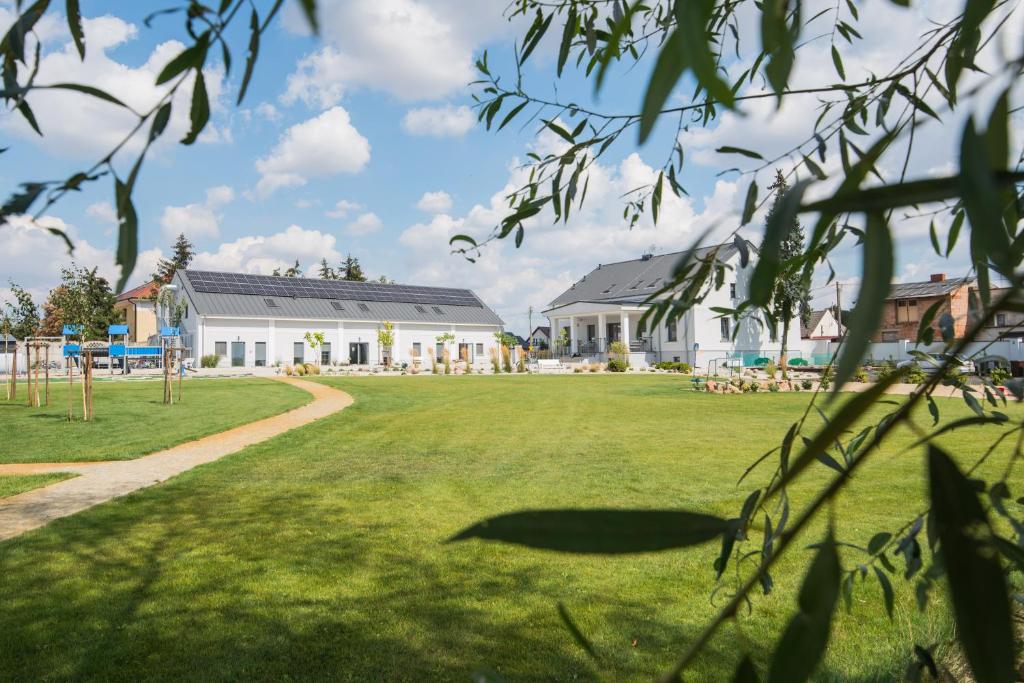 ein großer Rasenplatz mit Gebäuden im Hintergrund in der Unterkunft Folwark Matecznik in Sęzinko