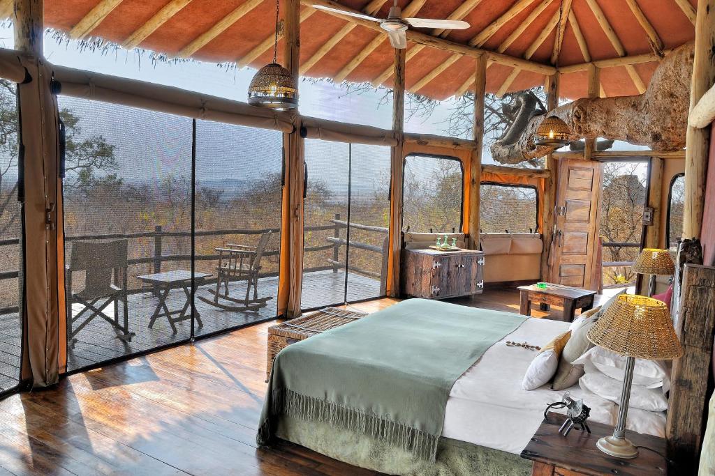 a bedroom with a bed in a room with a balcony at Tarangire Treetops in Kwa Kuchinia