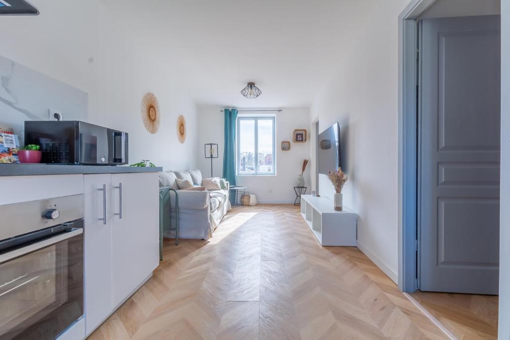 a kitchen and living room with white walls and wooden floors at Le Longeville in Longeville-lès-Metz