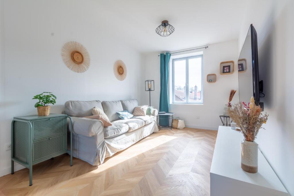 a white living room with a couch and a window at Le Longeville in Longeville-lès-Metz