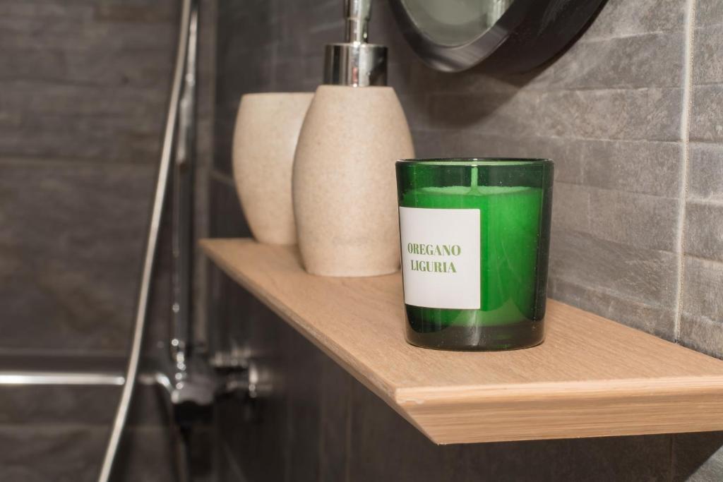 a green candle sitting on a wooden shelf in a bathroom at Le Longeville in Longeville-lès-Metz