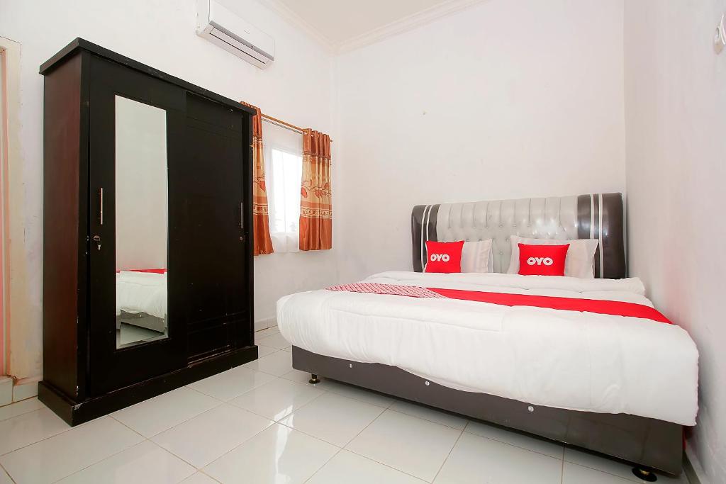 a bedroom with a bed with red pillows and a mirror at OYO 1847 Jasmine Kost Syariah in Jambi