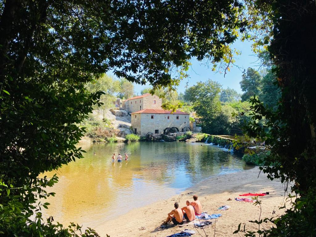 un grupo de personas sentadas en la playa al lado de un río en Azenha do Tio Luís, en Caminha