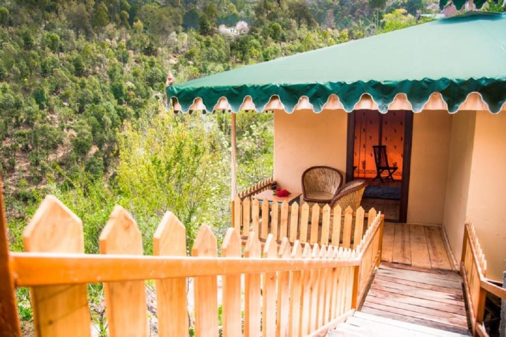une terrasse couverte d'une maison avec une clôture en bois dans l'établissement EVAAN RESORTS THE FOLIAGE, à Mukteswar