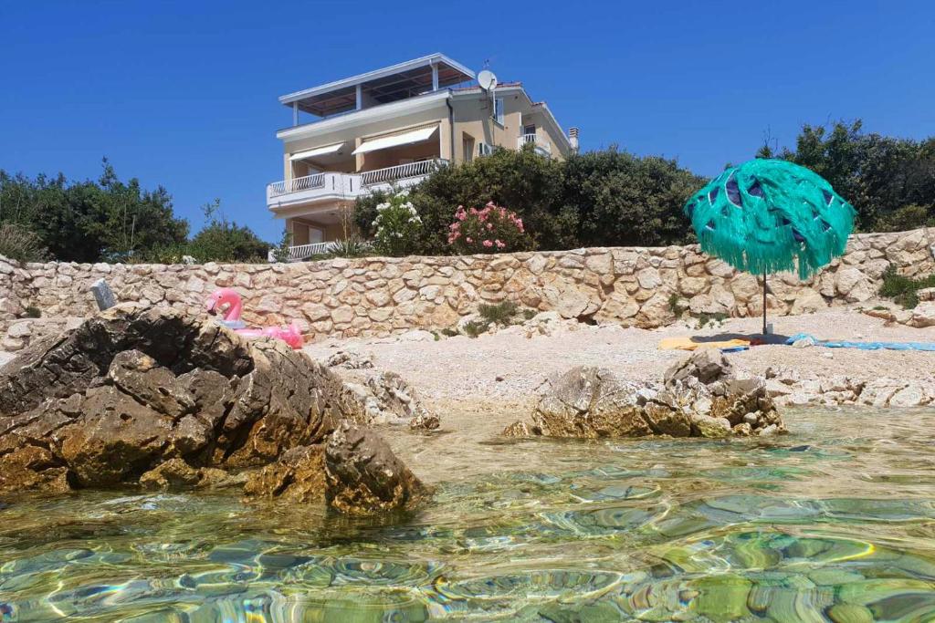 une plage avec un parasol et une maison dans l'établissement Apartments by the sea Mandre, Pag - 6386, à Kolan