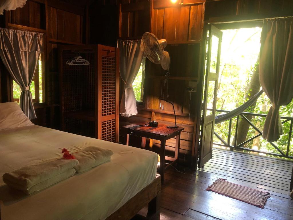 a bedroom with a bed and a large window at Bambu Huts in Ban Tai