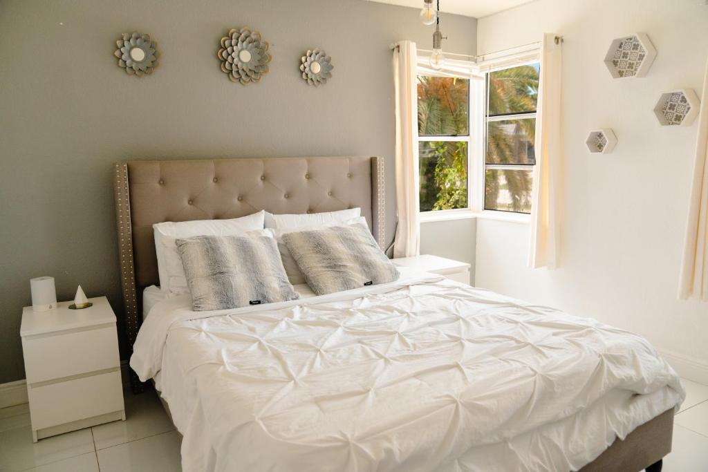 sypialnia z łóżkiem z białą pościelą i oknem w obiekcie Light & Cozy House in Pompano Beach - BBQ, Patio, Parking w mieście Pompano Beach
