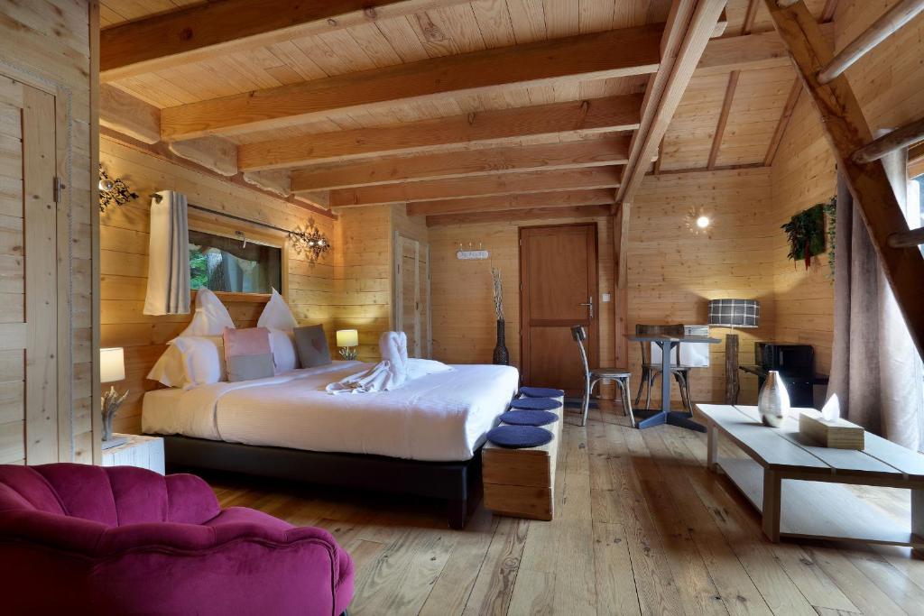 a bedroom with a large bed and a table at Les Lodges de Babylone in Larringes