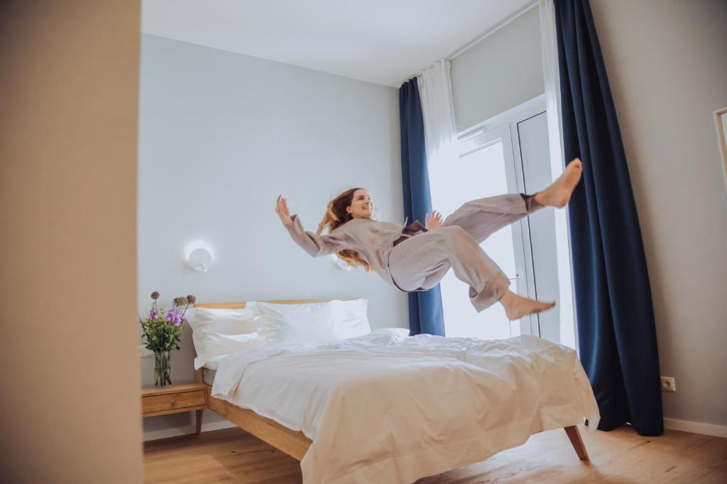 uma mulher a saltar para cima de uma cama em The Layhead B&B em Lübeck