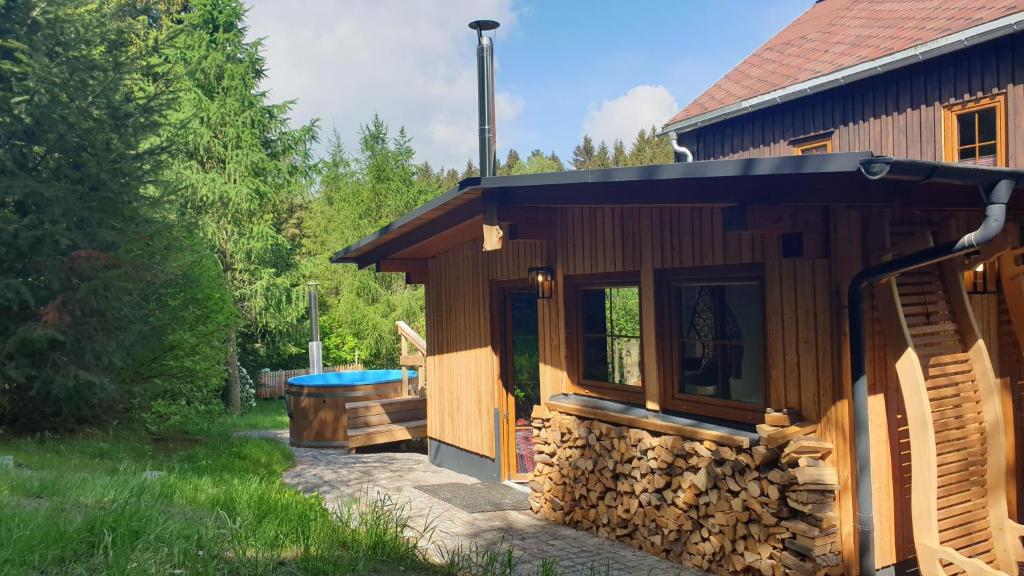 a cabin with a pile of wood next to a tub at hutzenAlm in Nassau