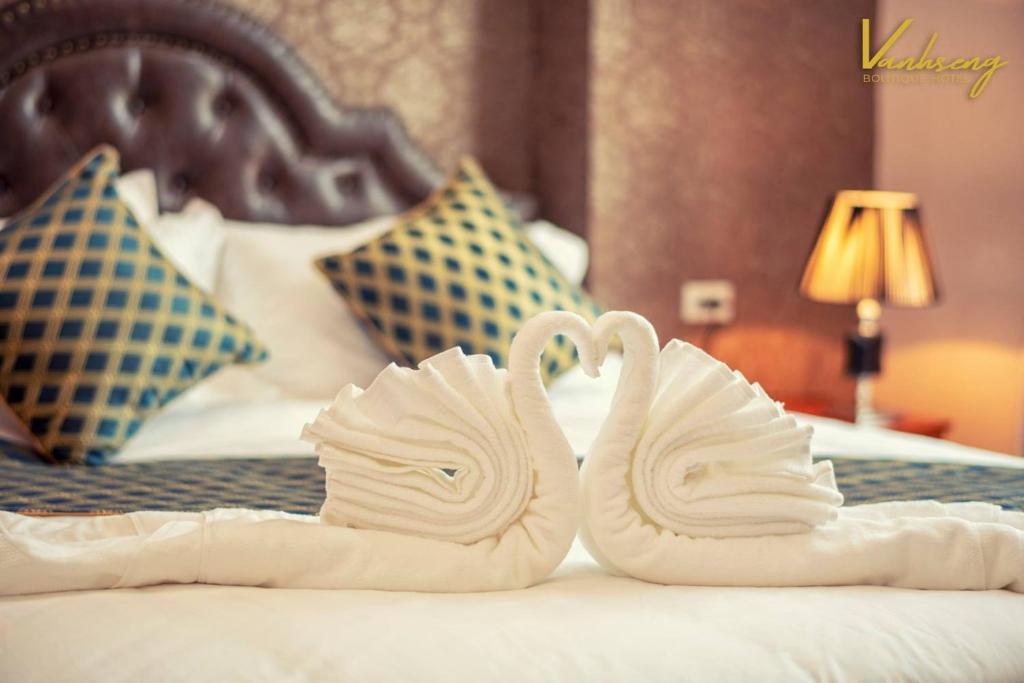 dois cisnes feitos de toalhas numa cama em VANHSENG BOUTIQUE VIENTIANE HOTEL em Vientiane