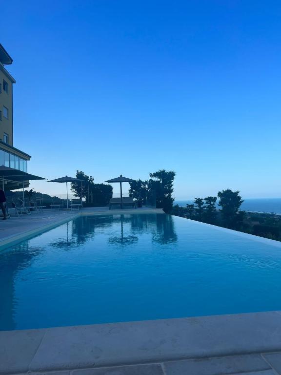 una grande piscina di acqua blu accanto a un edificio di Hotel Bellavista a Porto San Giorgio