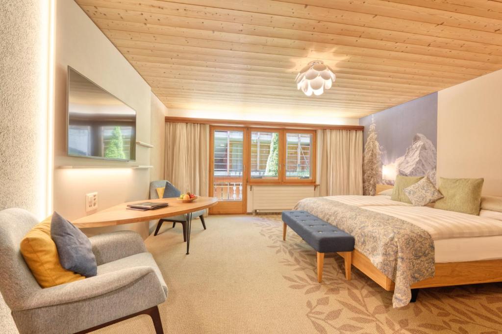 ein Schlafzimmer mit einem Bett, einem Schreibtisch und einem Stuhl in der Unterkunft Hotel Simi in Zermatt