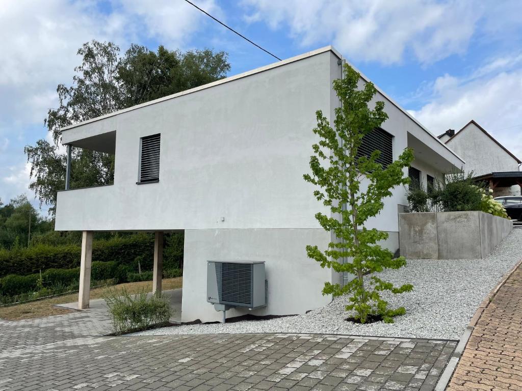 Una casa blanca con un árbol delante. en Ferienhaus Simon, en Wadern