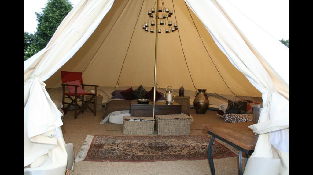 Tienda con sofá y mesa. en Home Farm Radnage Glamping Bell Tent 7, with Log Burner and Fire Pit, en High Wycombe