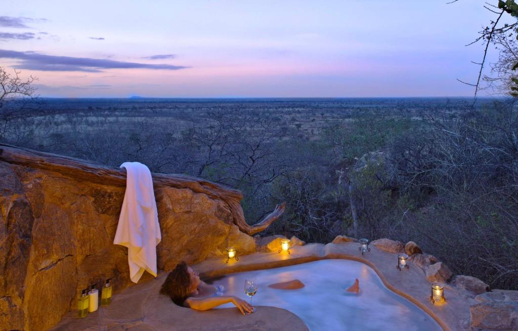 a woman laying in a hot tub on a cliff at Elewana Elsa's Kopje in Meru