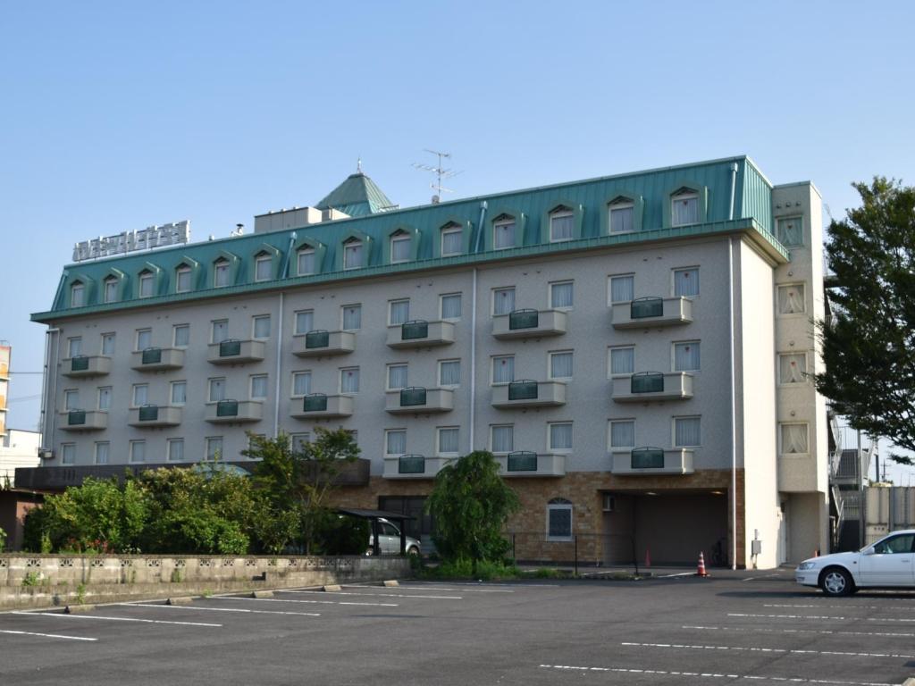 a building with a car parked in a parking lot at Hotel Castle Inn Suzuka Chuo in Suzuka