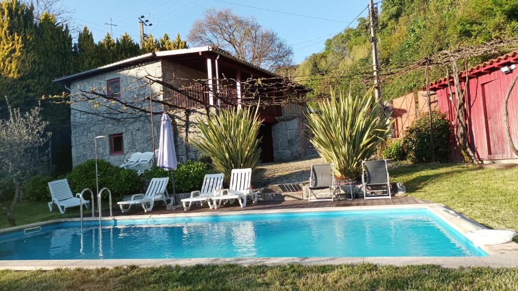 a swimming pool with chairs and a house at Quinta do Pontido in Vieira do Minho