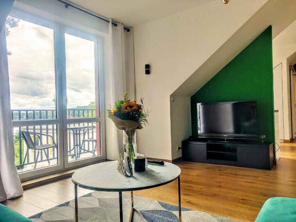 uma sala de estar com televisão e uma mesa com flores em Zielony apartament z widokiem na jezioro em Złotów