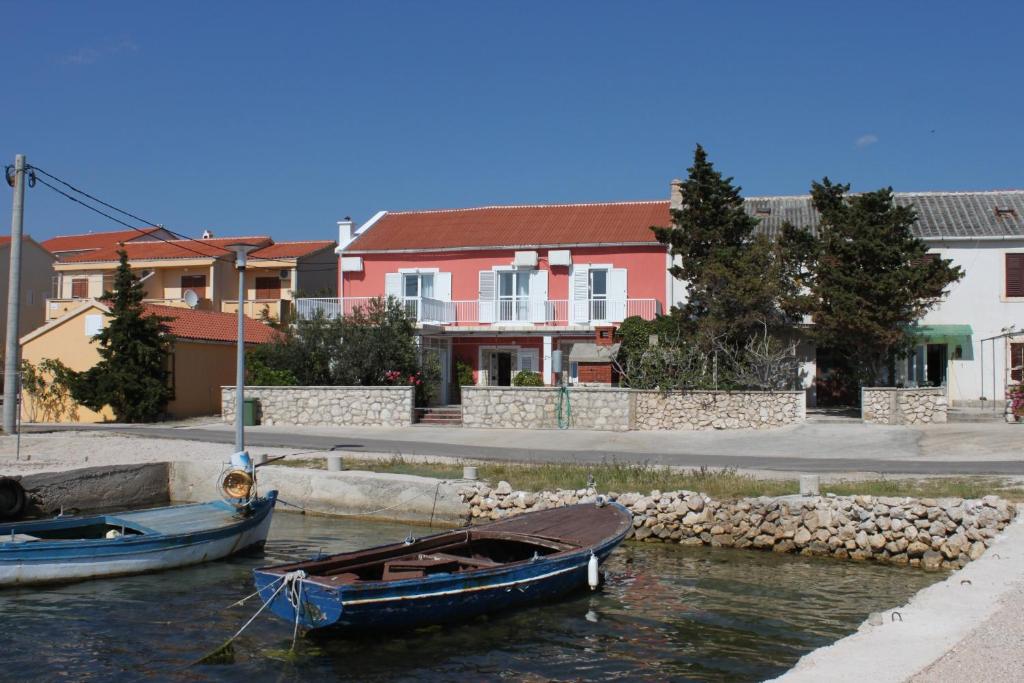 Deux bateaux sont amarrés dans l'eau à côté des maisons dans l'établissement Rooms by the sea Kustici, Pag - 6288, à Kustići