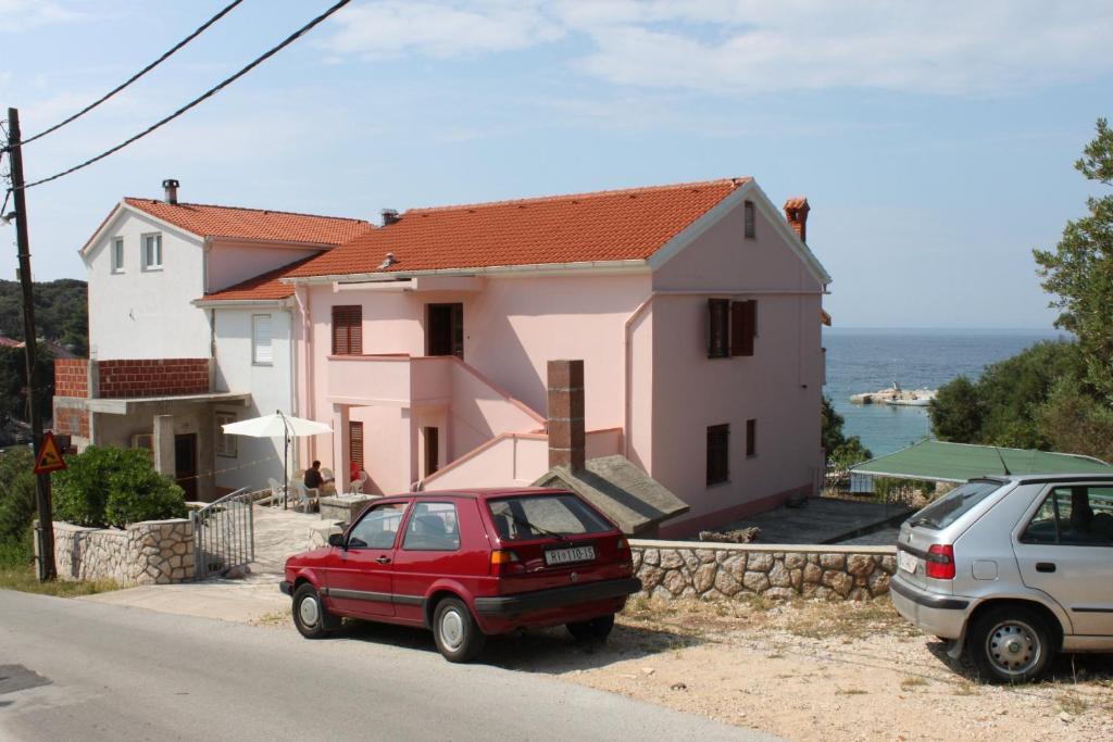 a red car parked in front of a house at Apartments by the sea Jakisnica, Pag - 6424 in Lun
